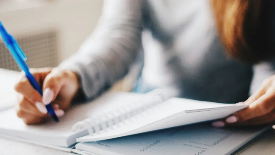 Persona completando documentos sobre un escritorio
